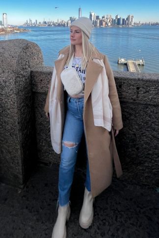 a photo of a woman wearing a brown coat and blue jeans